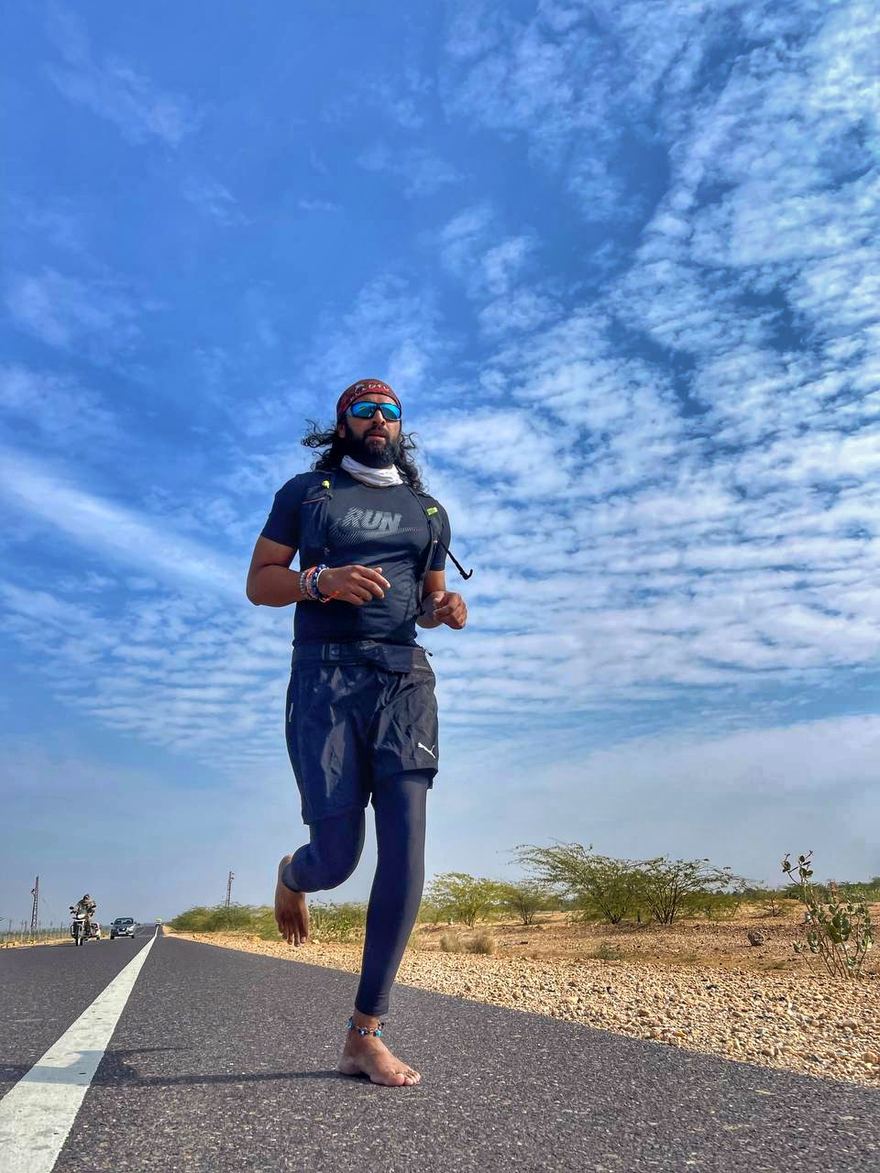 Aakash Nambiar running barefoot on an open desert highway near Dubai